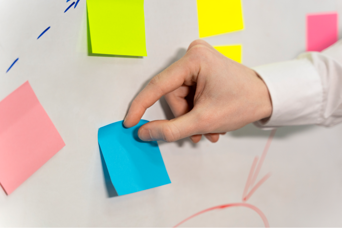 hand sticking blue post it board